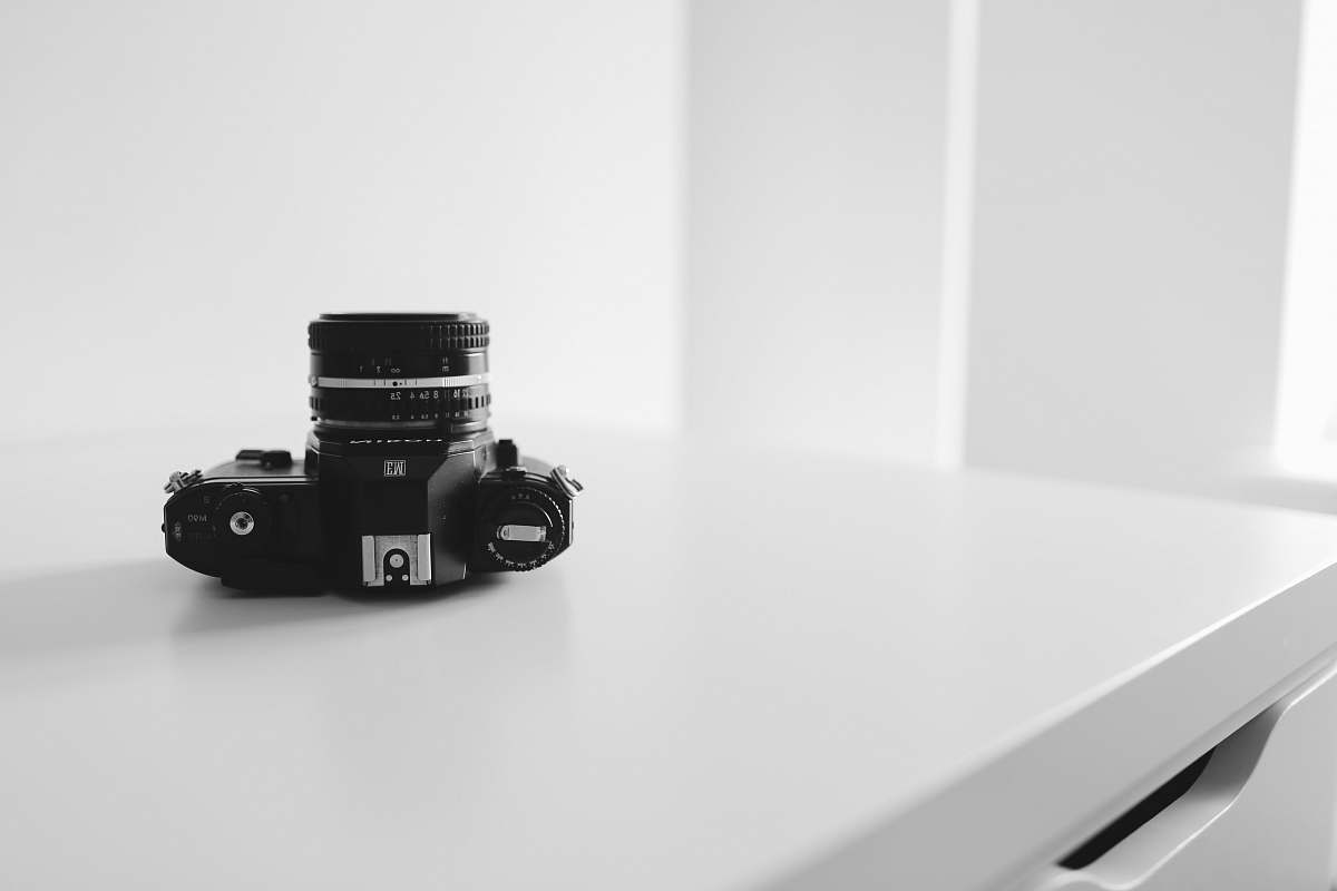 camera black DSLR camera on white surface electronics