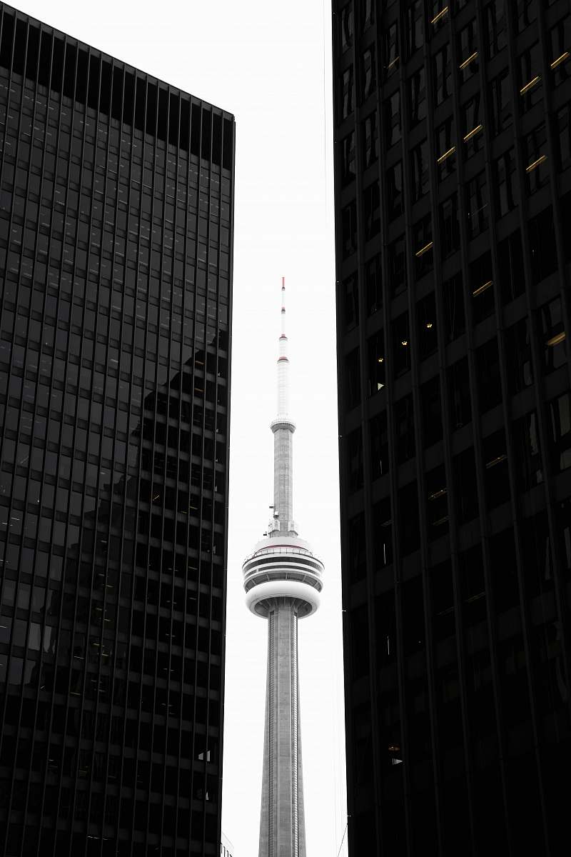 building CN tower in between glass skyscrapers toronto