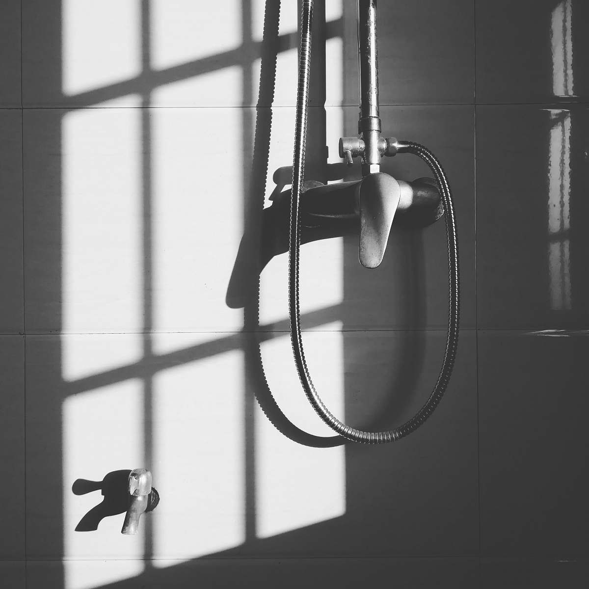pole gray stainless steel shower head hanged on wall during daytime shower