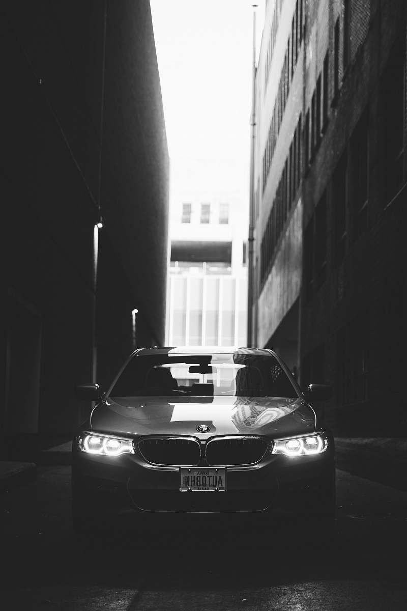 vehicle grayscale photo of BMW car parked between buildings car
