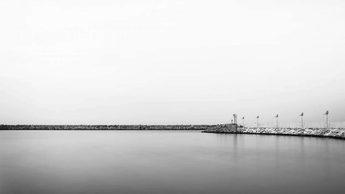 water grayscale photo of body of water near poles waterfront