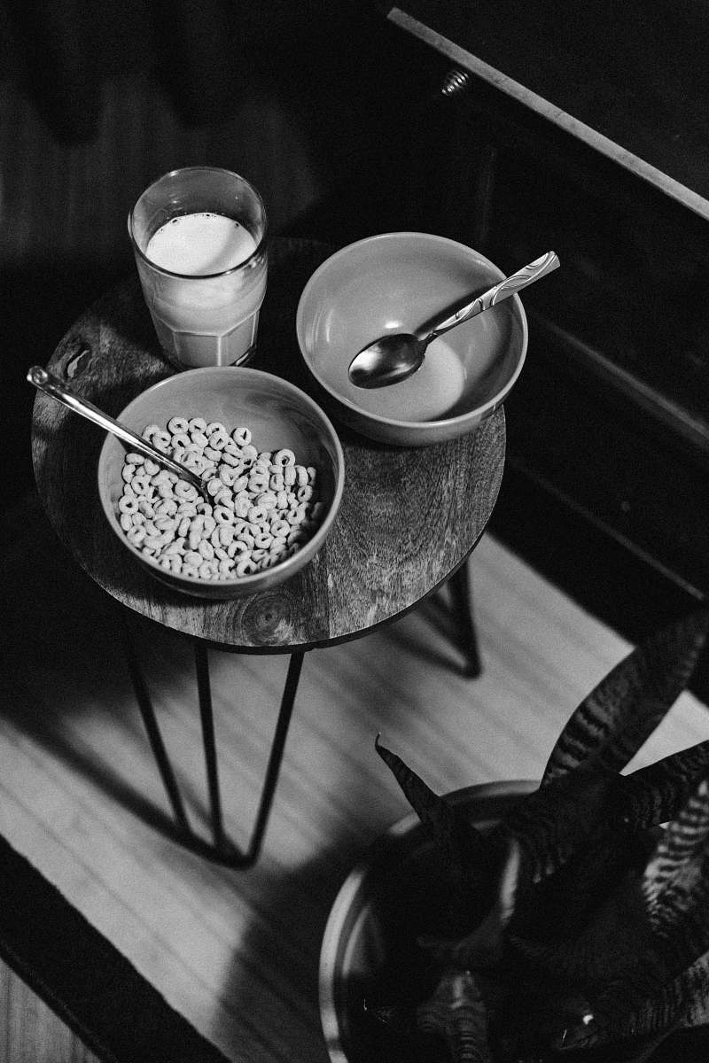 spoon grayscale photo of bowl of cereal beside glass of milk cutlery