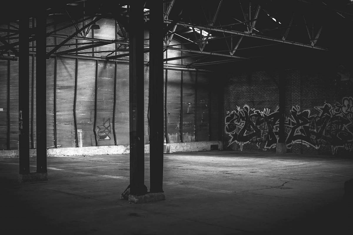 grey grayscale photo of building with walls painted with graffiti underground