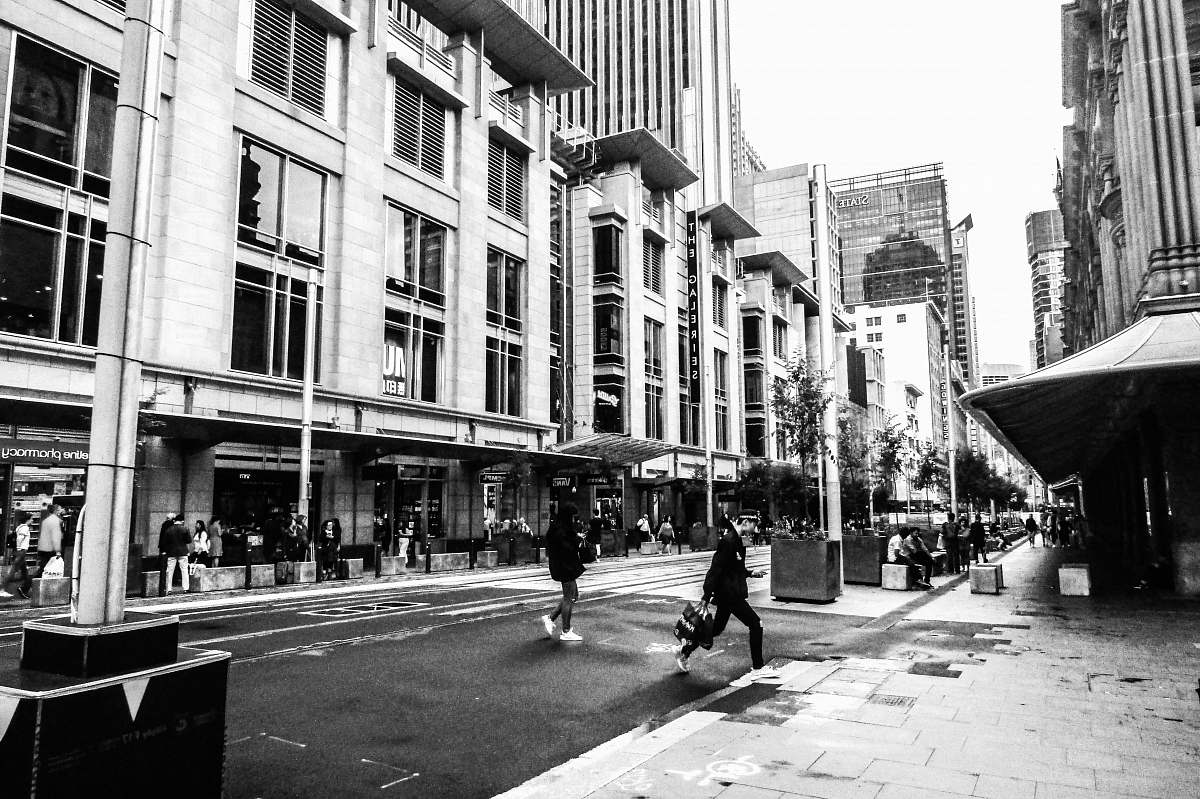 city grayscale photo of concrete buildings sidewalk