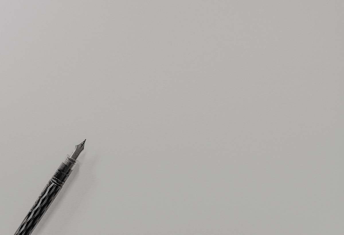 grey grayscale photo of fountain pen flying
