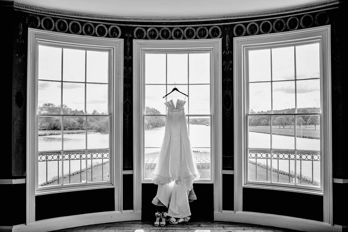 window grayscale photo of gown hanged on window person