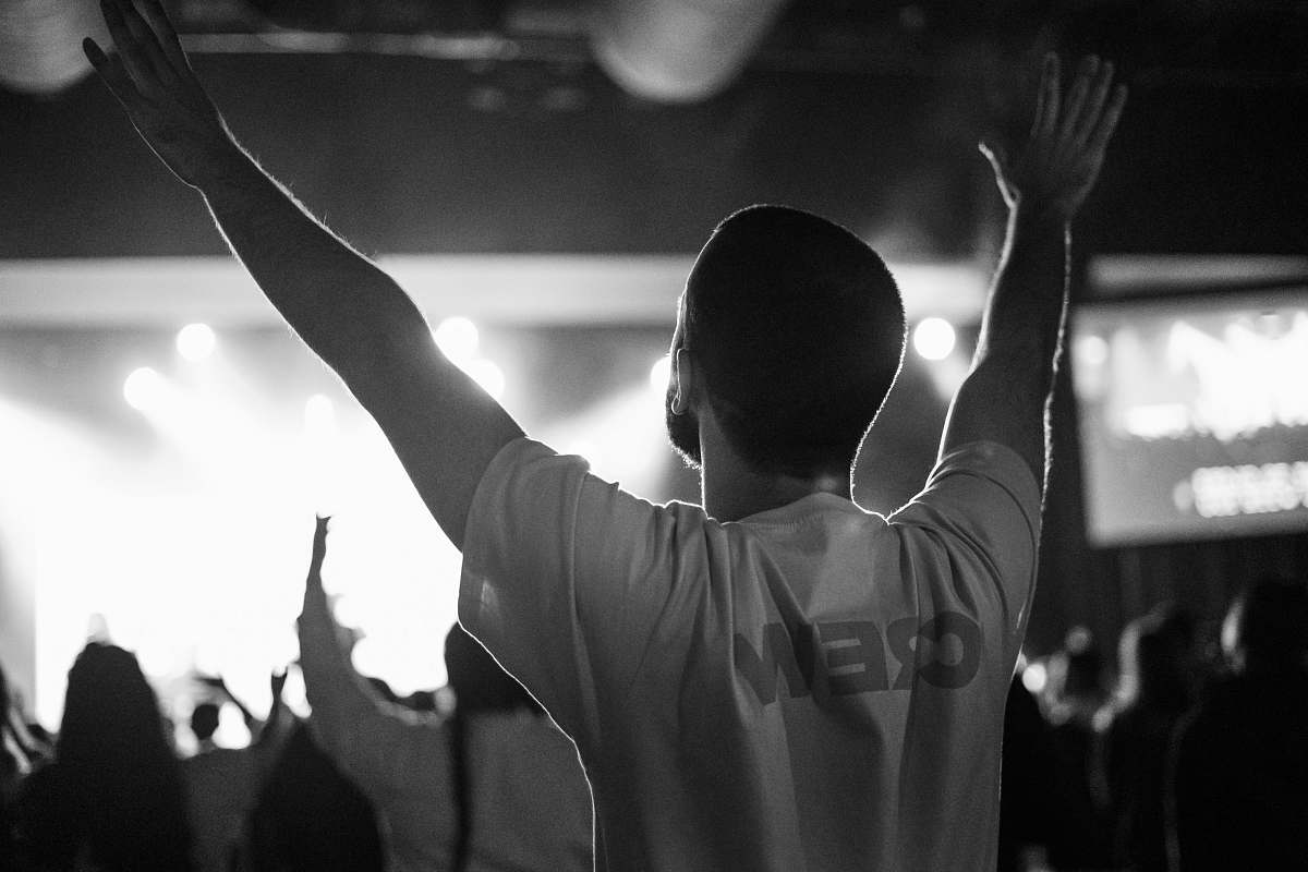 human grayscale photo of man in crew-neck shirt raising both hands person