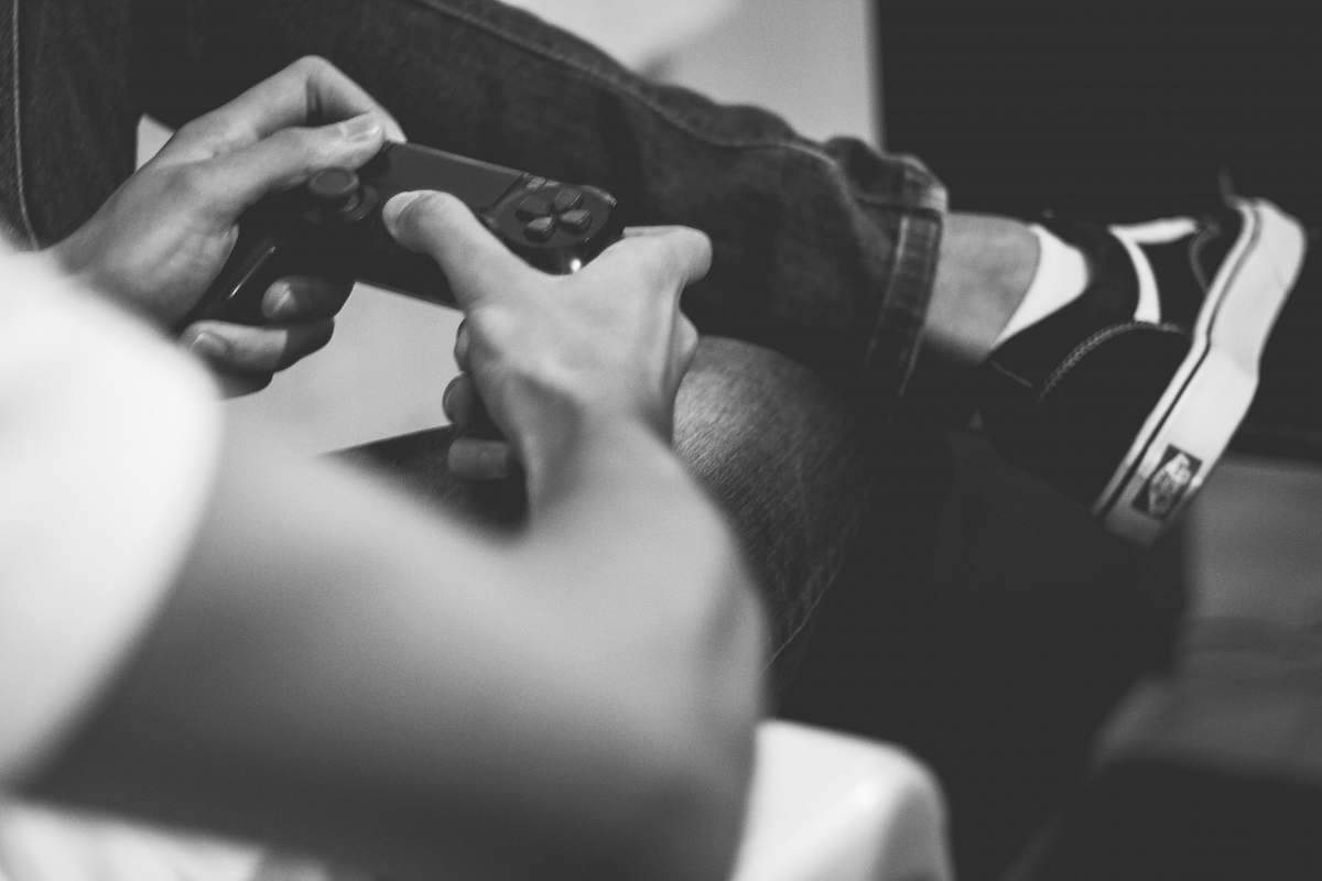 human grayscale photo of man playing on game controller grey