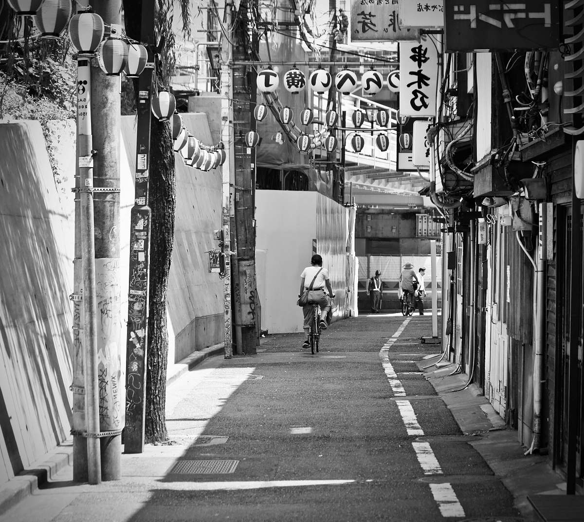 city grayscale photo of man riding bike street