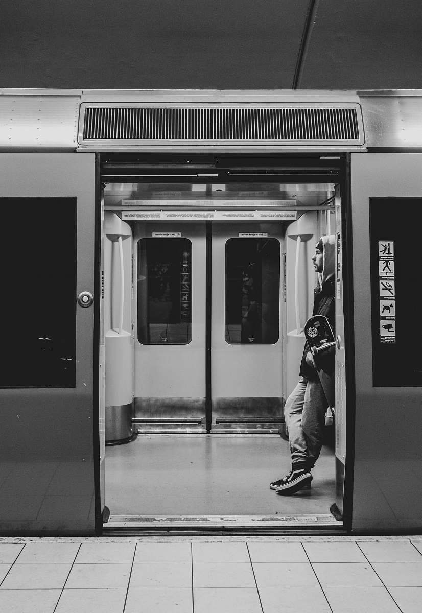 terminal grayscale photo of man standing in train entrance train