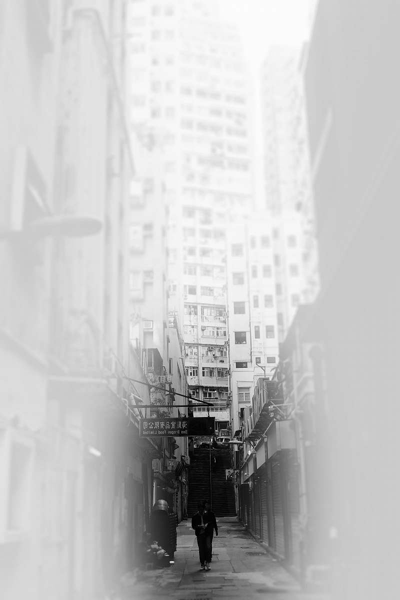 human grayscale photo of person near buildings person