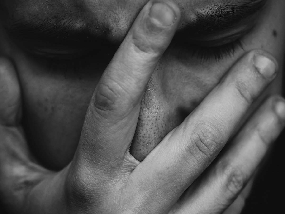 grey grayscale photo of person placing hand on face human