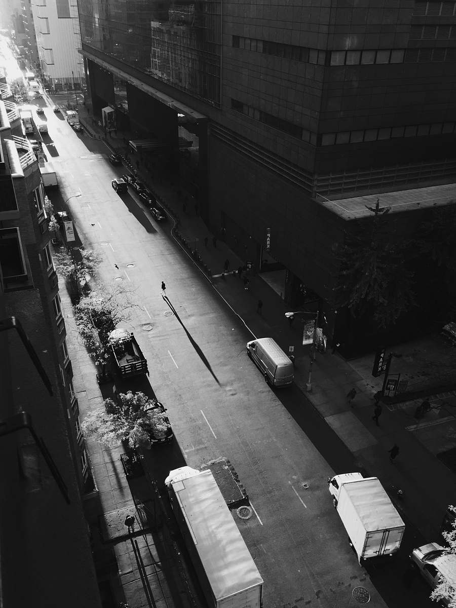 city grayscale photo of person walking on road outside building building