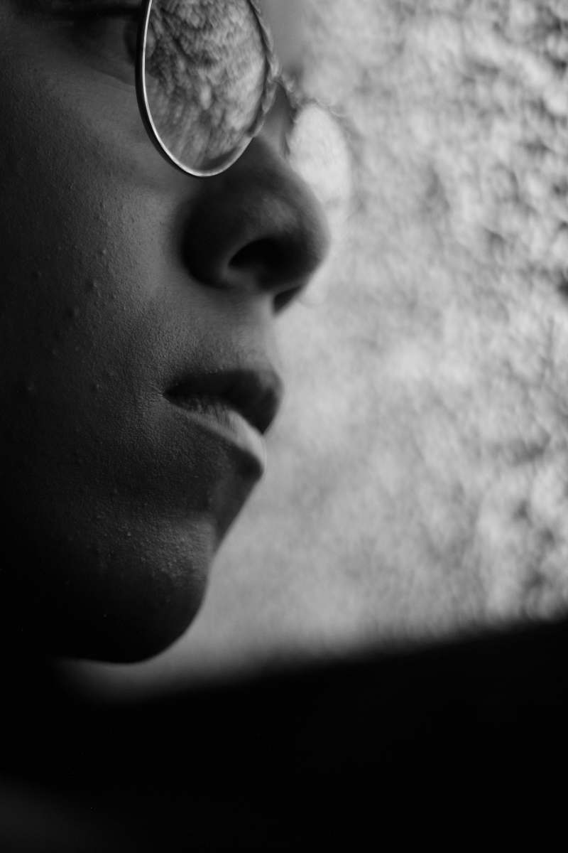 head grayscale photo of person wearing eyeglasses looking at glass face