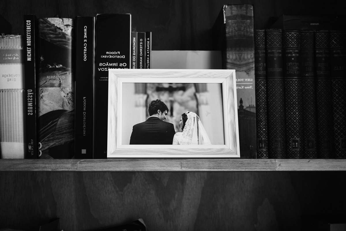 human grayscale photo of photo frame on wooden shelf book