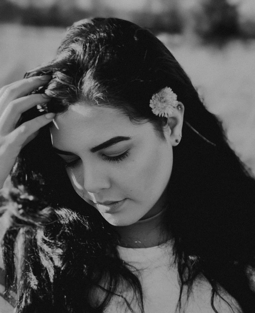 person grayscale photo of woman closing her eyes while holding hair human