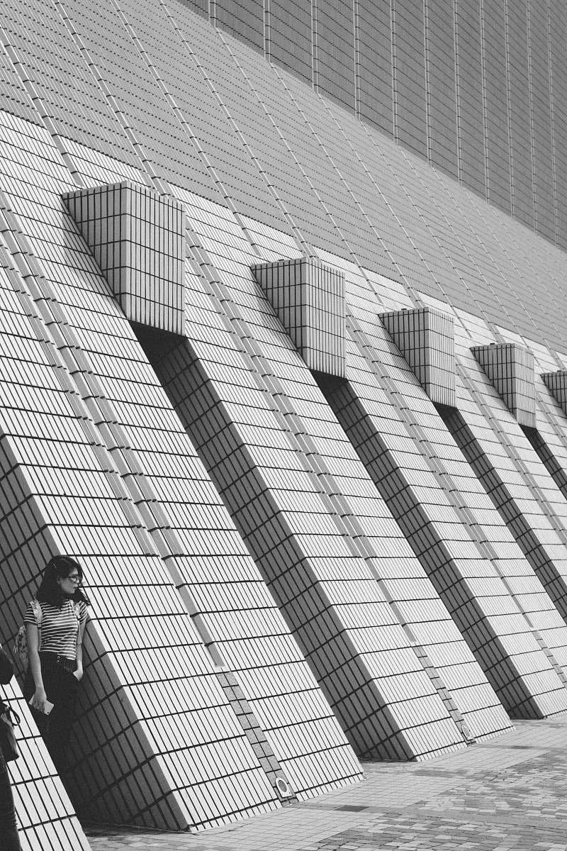 grey grayscale photo of woman leaning on wall hong kong
