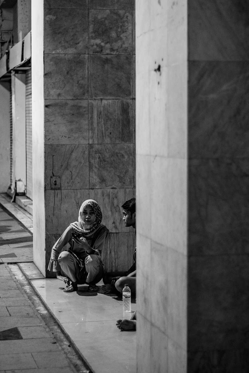 human grayscale photo of woman sitting on gray surface person