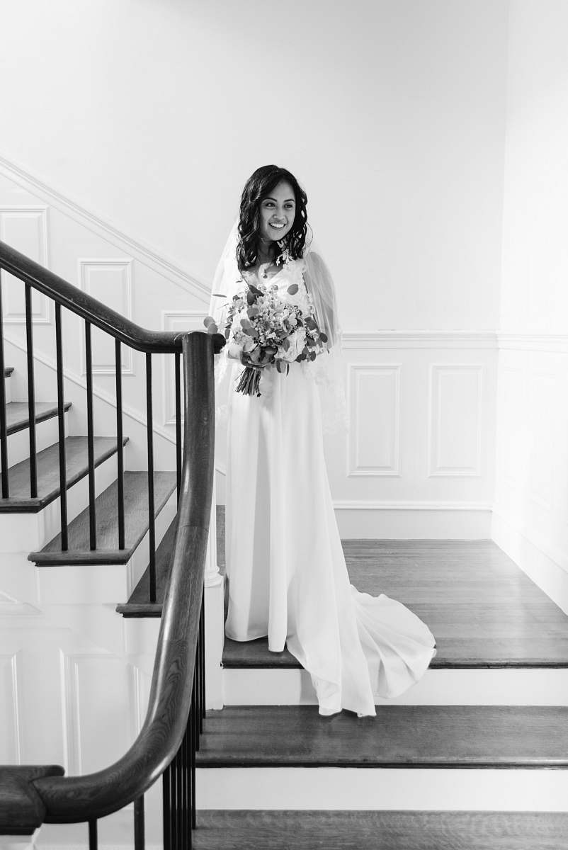 clothing grayscale photo of woman standing on stairs in wearing dress and smiling apparel
