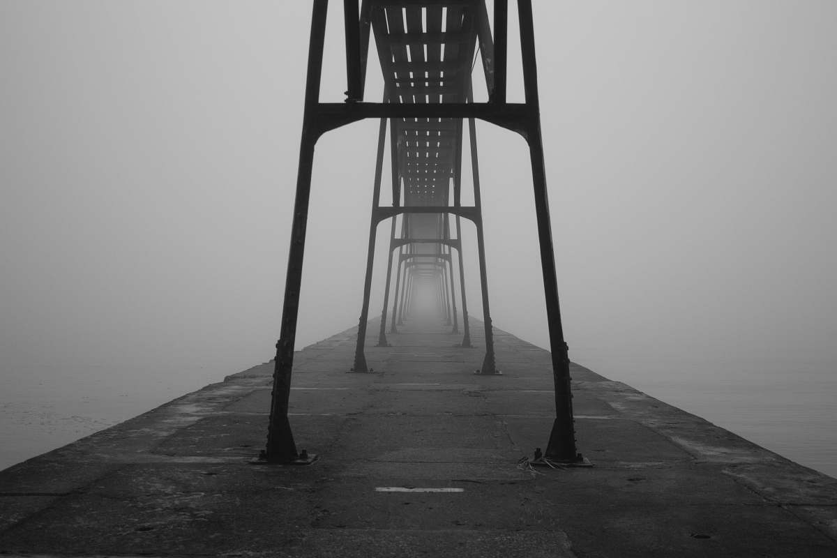 grey grayscale photograph of bridge between body of water pier