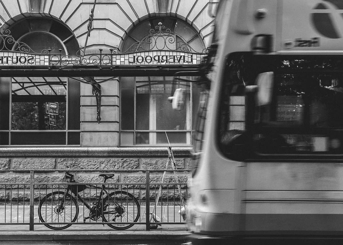 grey grayscale photography of bicycle parked at steel fence bus