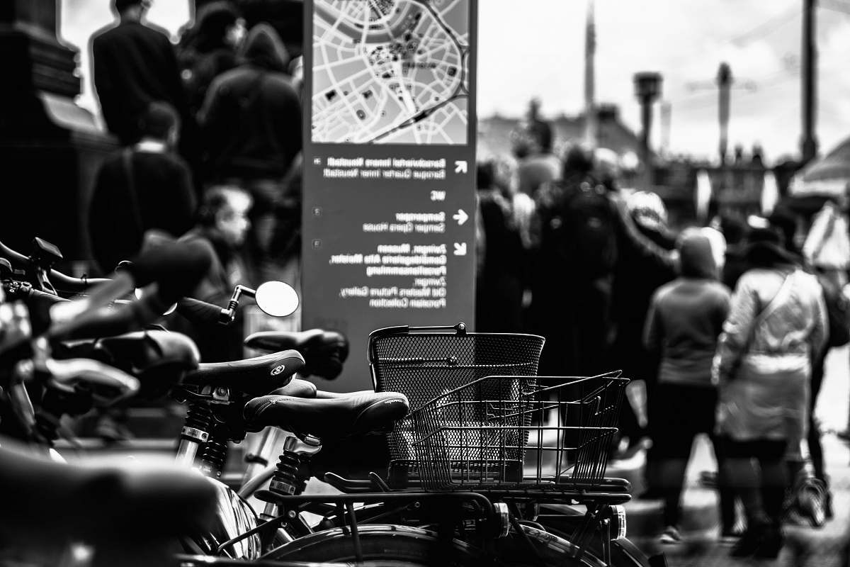 human grayscale photography of bikes near walking people people