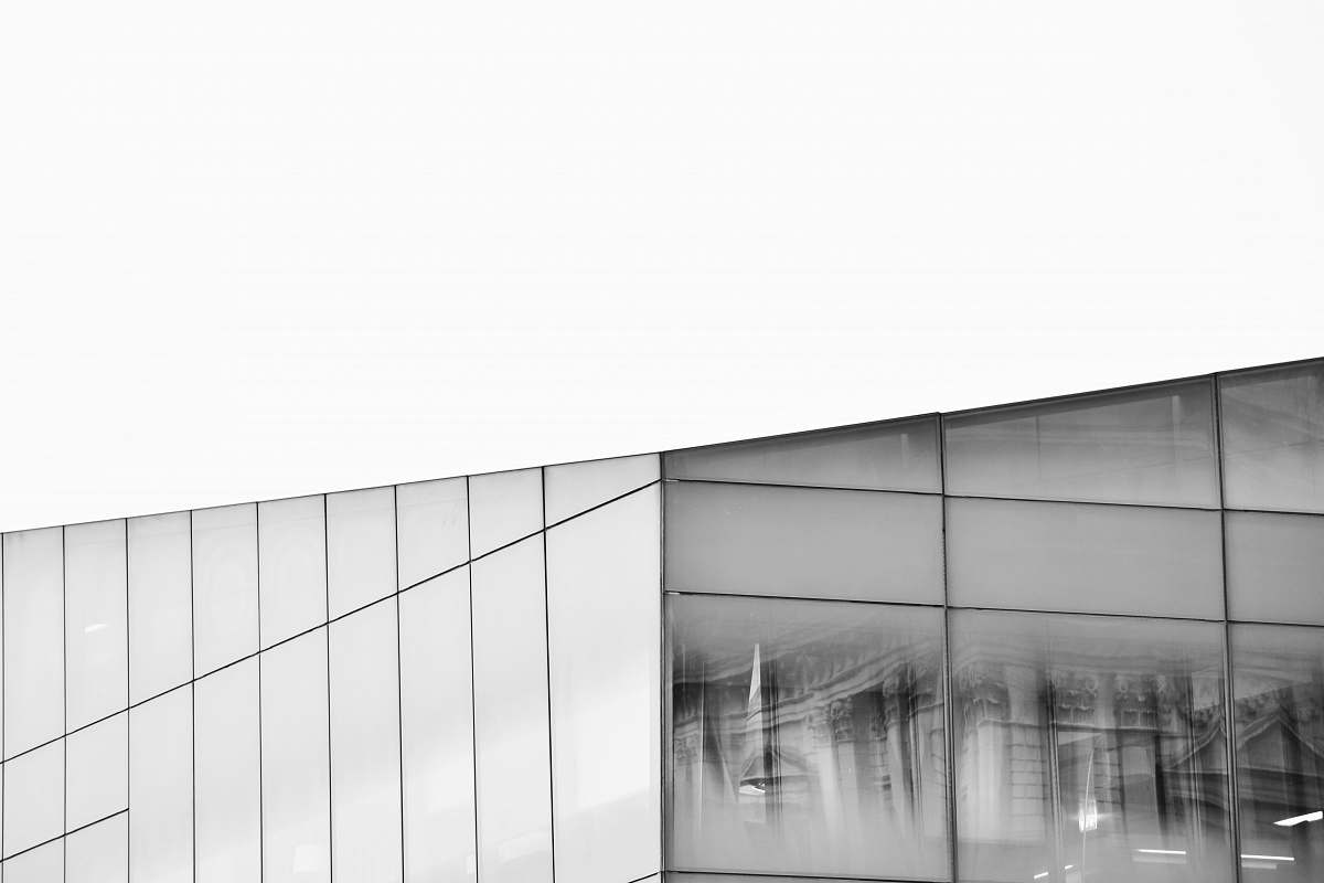Experience the captivating allure of this grey grayscale photograph showcasing the intricate reflections on a glass building's window. The high-contrast black and white imagery emphasizes the architectural lines and symmetry, making it an ideal choice for design projects, editorial use, or as an eye-catching background in digital media. Perfect for those seeking a touch of elegance and modernity in visual storytelling.