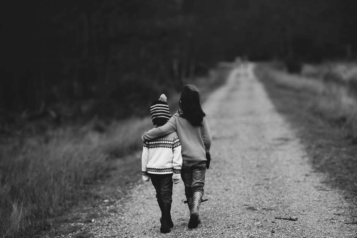 people grayscale photography of kids walking on road family
