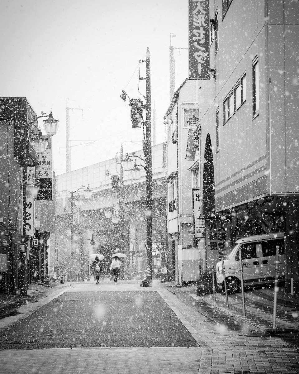 japan grayscale photography of man and woman holding umbrellas city