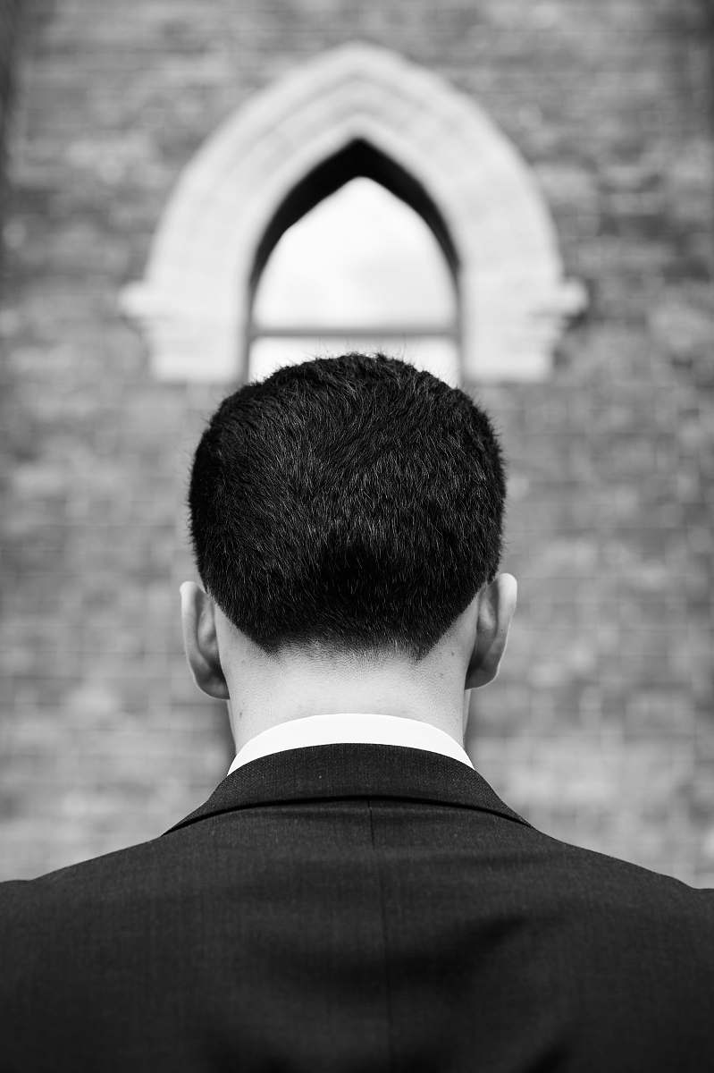 apparel grayscale photography of man facing back near wall clothing