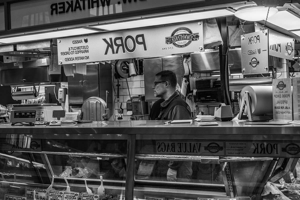 person grayscale photography of man inside pork food counter human