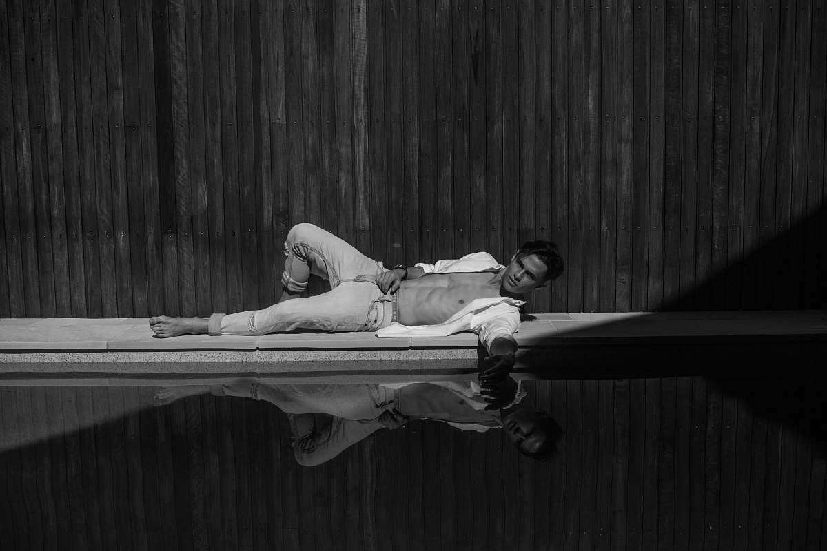 grey grayscale photography of man laying near swimming pool australia