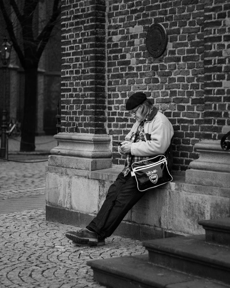 human grayscale photography of man leaning on wall person