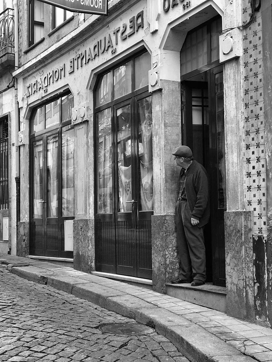 path grayscale photography of man standing on doorway walkway