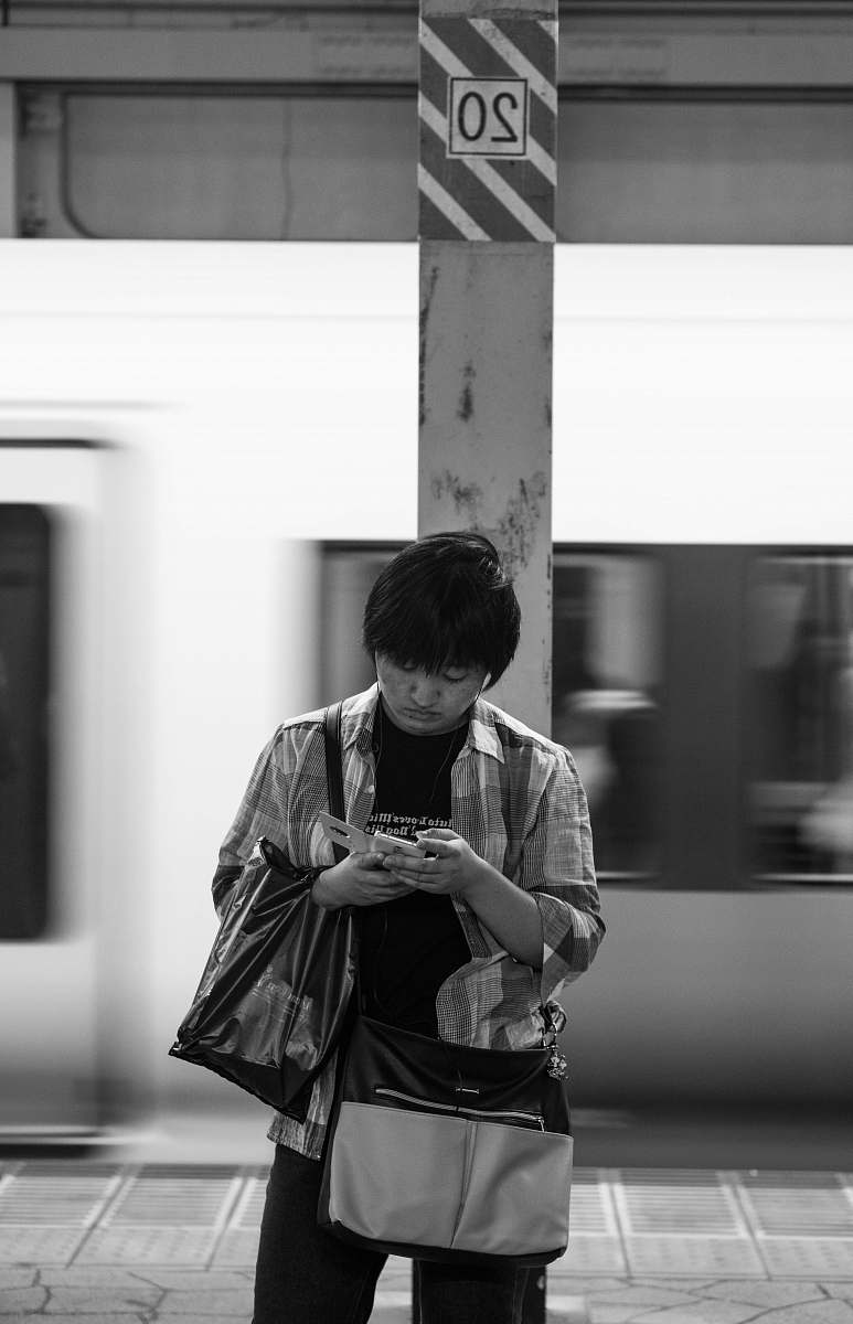 person grayscale photography of man using phone while standing human