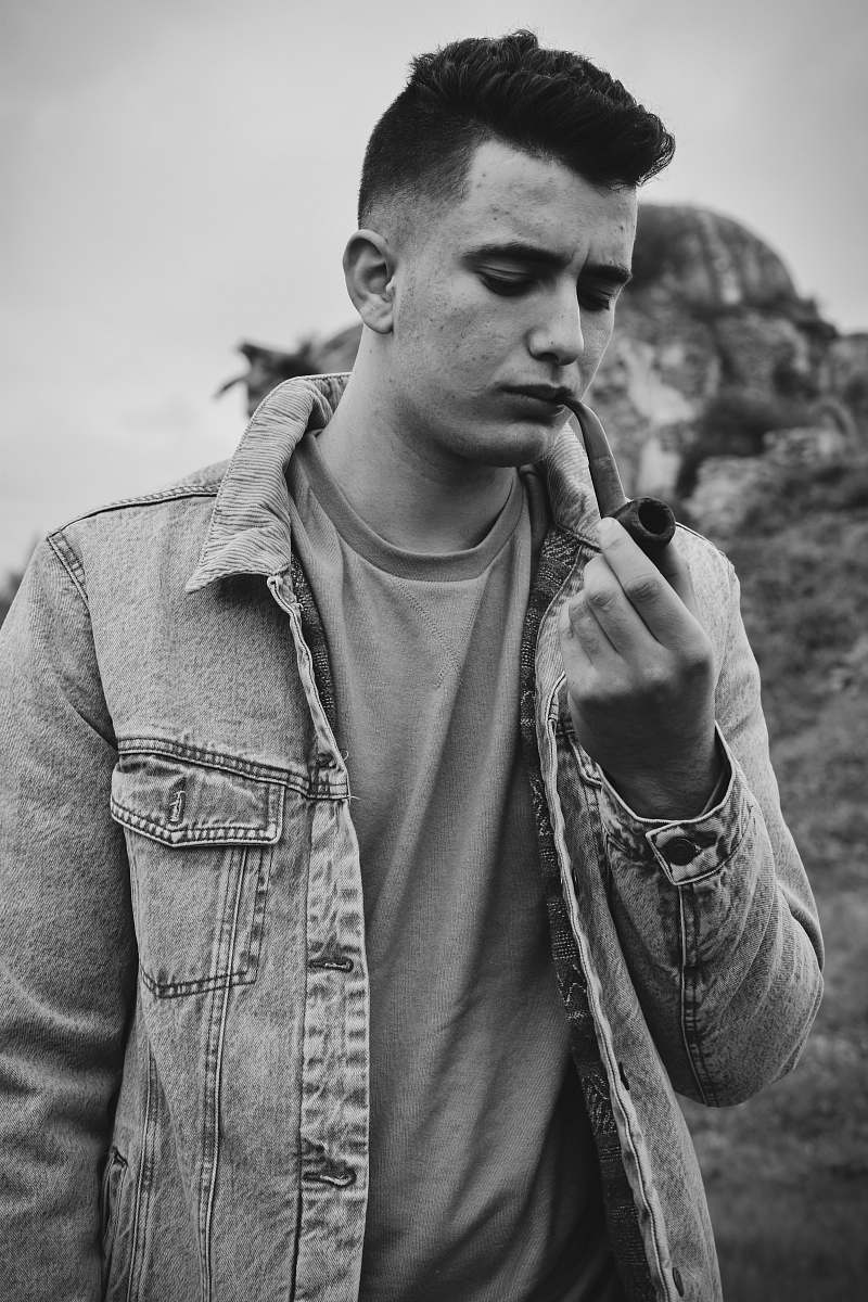 human grayscale photography of man using tobacco pipe person