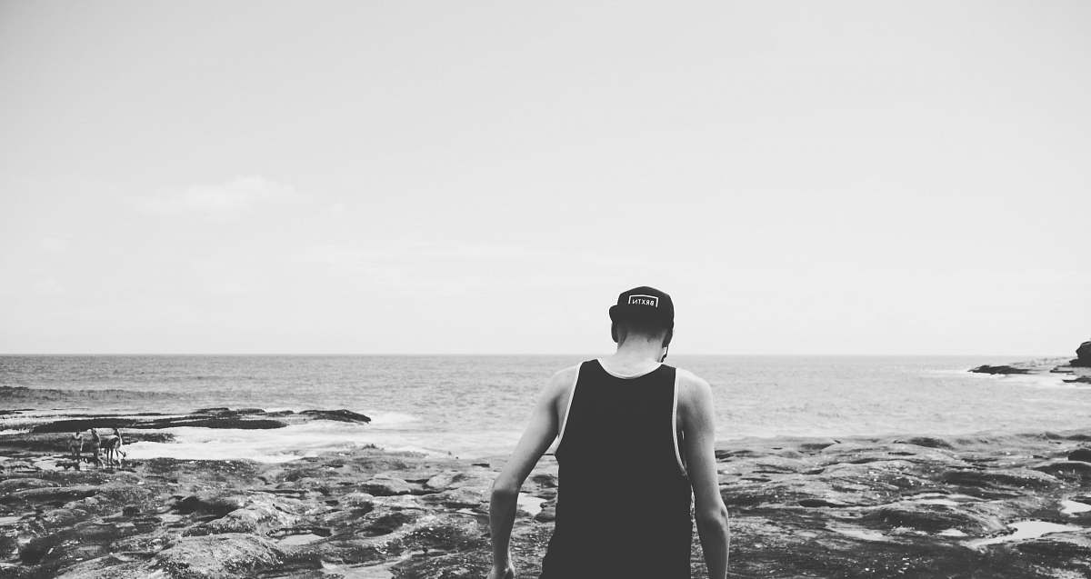 nature grayscale photography of man walking on shore outdoors