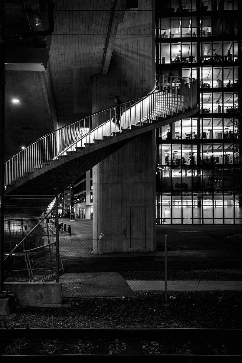 banister grayscale photography of person coming down spiral stairs handrail