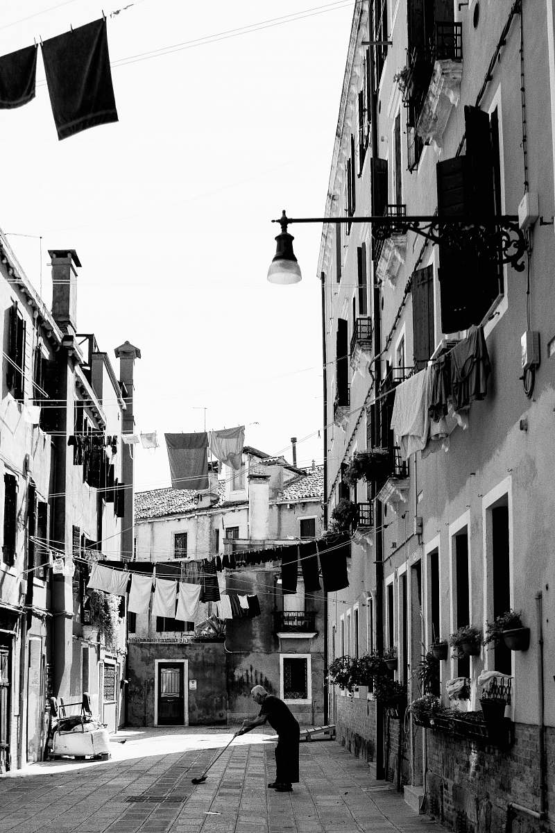 person grayscale photography of person on pathway near buildings human