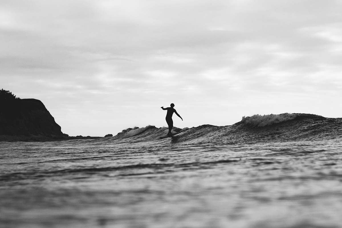 water grayscale photography of person surfing on sea ocean