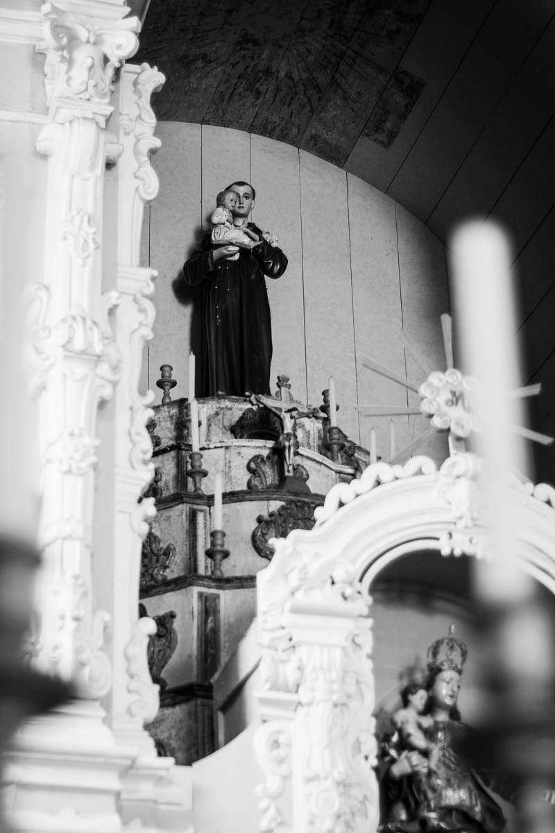 human grayscale photography of religious man carrying baby Jesus statue person