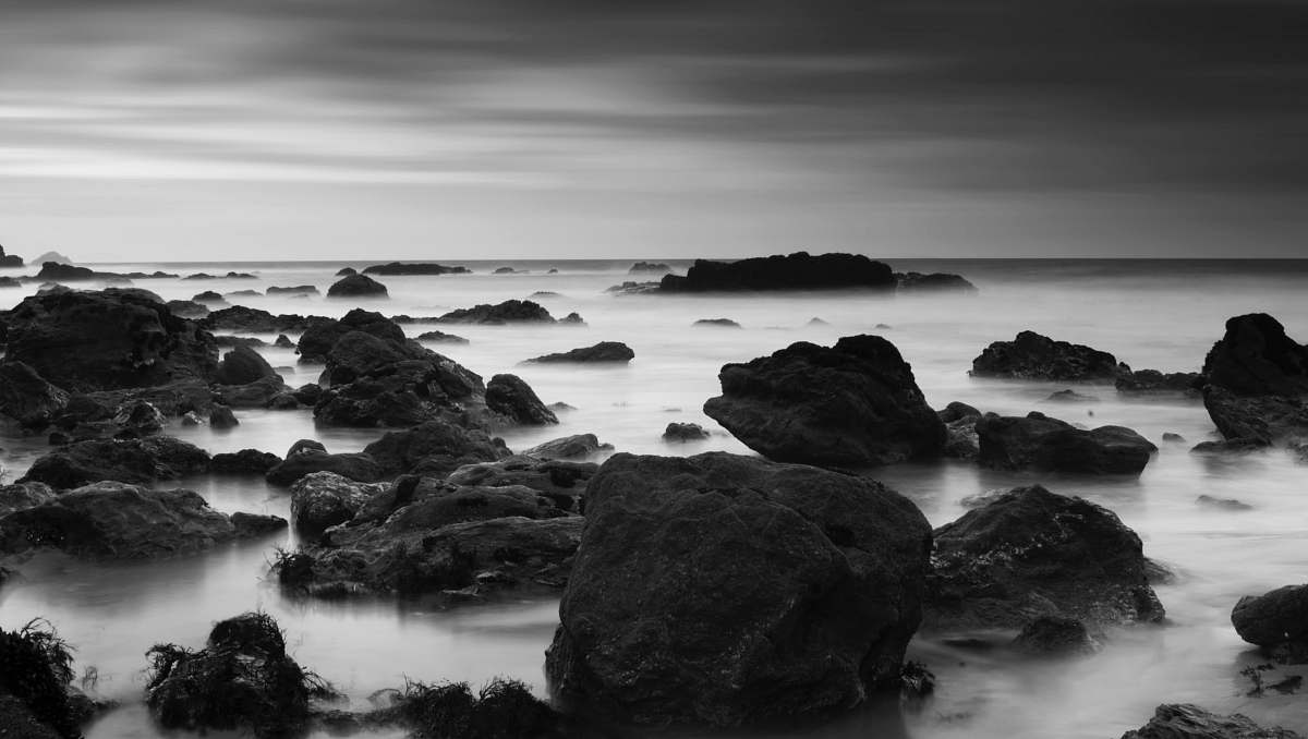 water grayscale photography of rocks on body of water rock