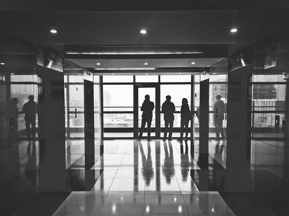 human grayscale photography of three person in building person