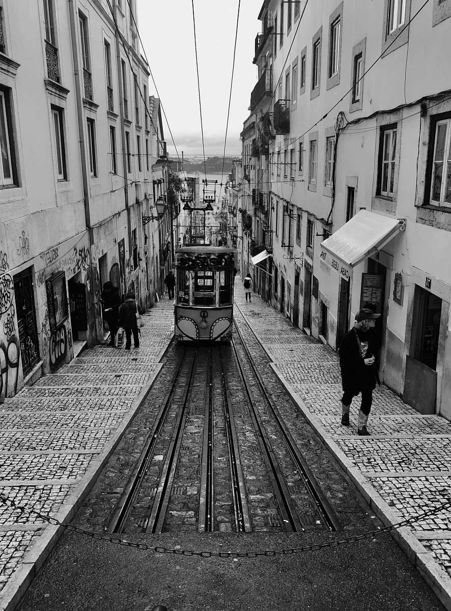 path grayscale photography of tram passing through ascending alley walkway