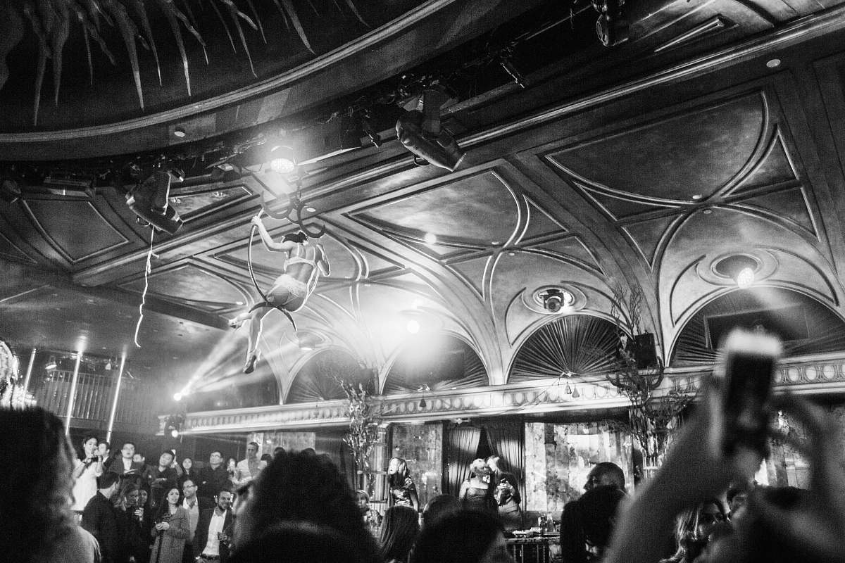 human grayscale photography of woman hanging near ceiling surrounded by crowd person