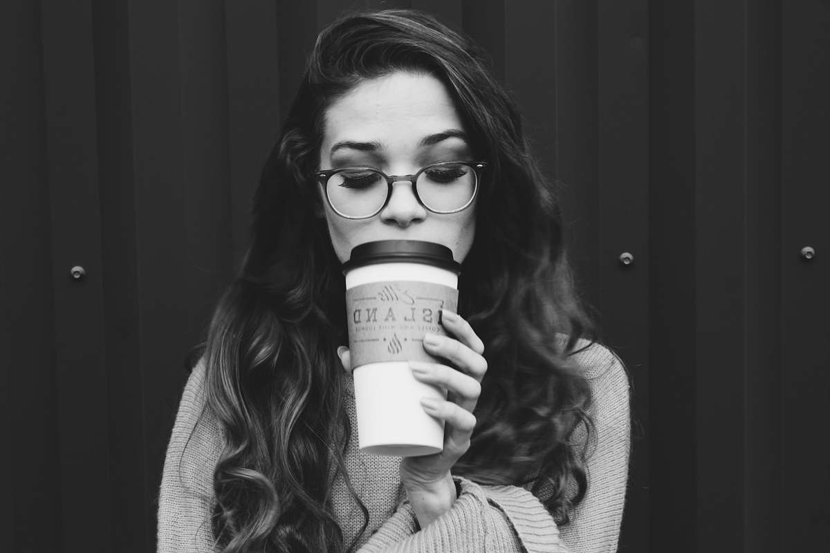 person grayscale photography of woman holding disposable cup people