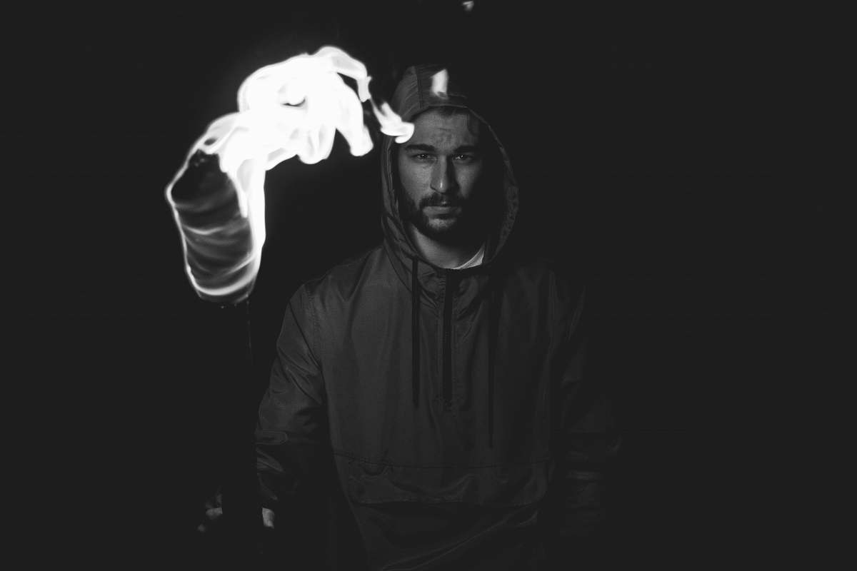 person grayscale shot of man holding torch human