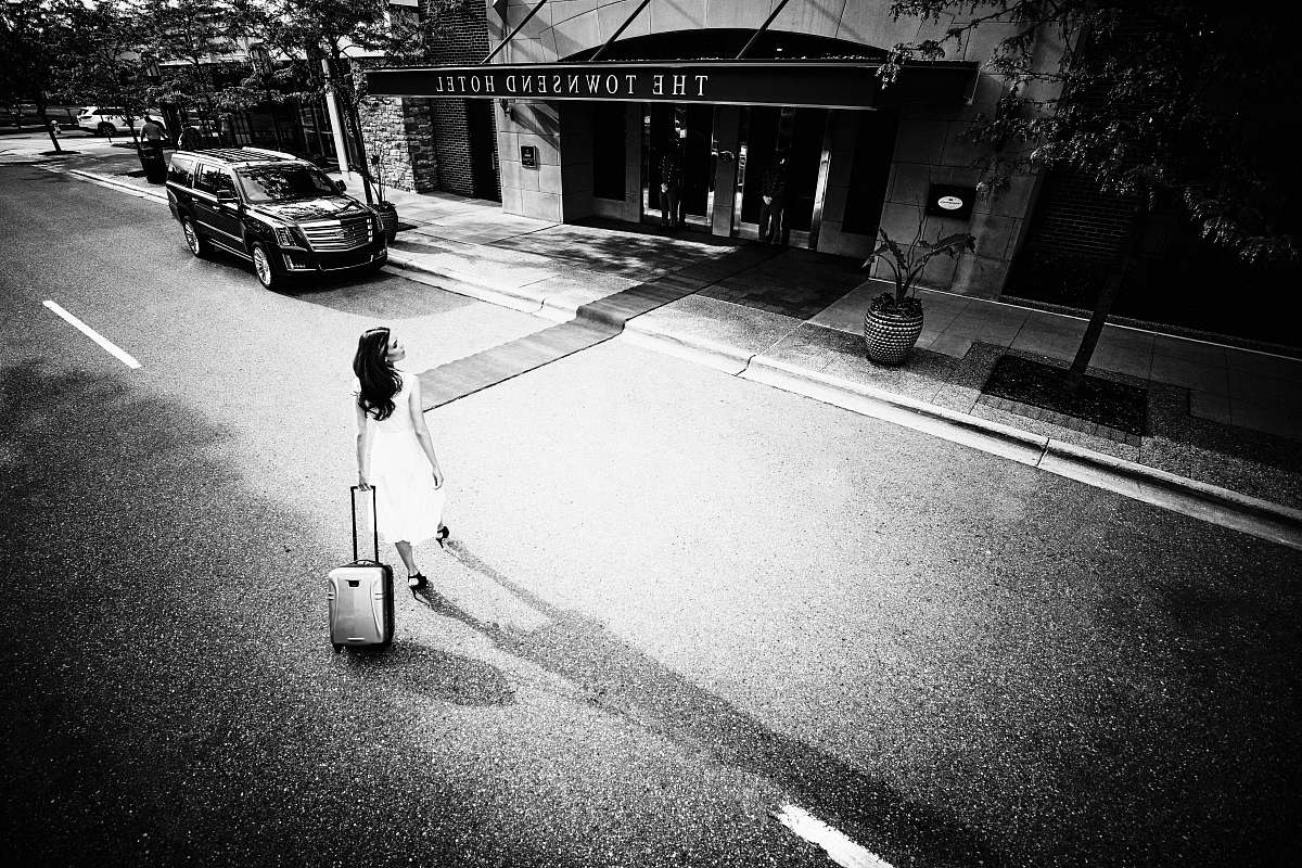 automobile greyscale of women pulling luggage bag car