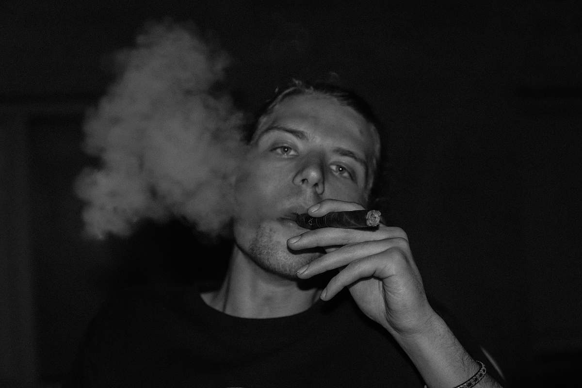 human greyscale photo of man smoking person