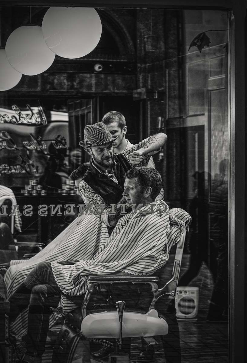 human man cutting a person's hair on chair person